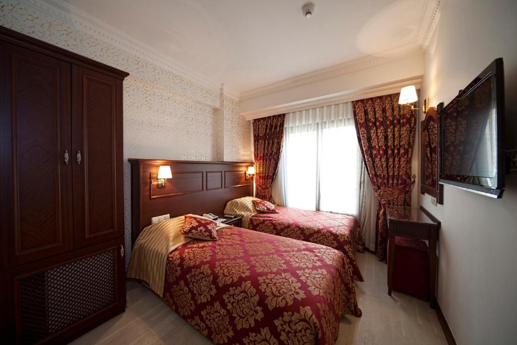 イスタンブールにあるIstanbul Newcity Hotelのベッド2台と窓が備わるホテルルームです。