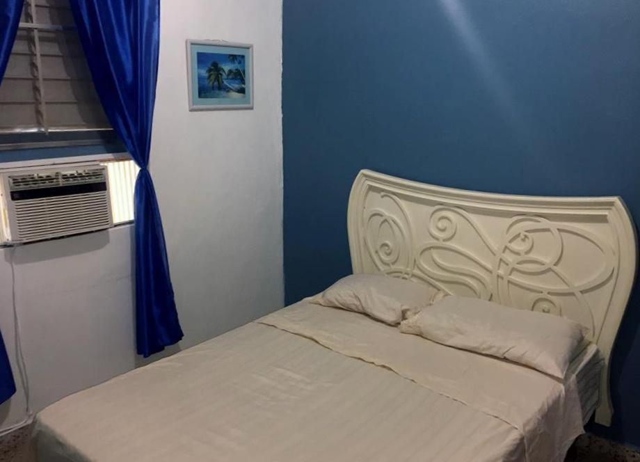 uma cama num quarto com uma parede azul em Brisas de Borinquen em Aguadilla