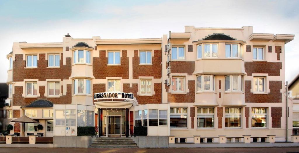 a large brick building with a sign on it at Ambassador Hotel in De Panne