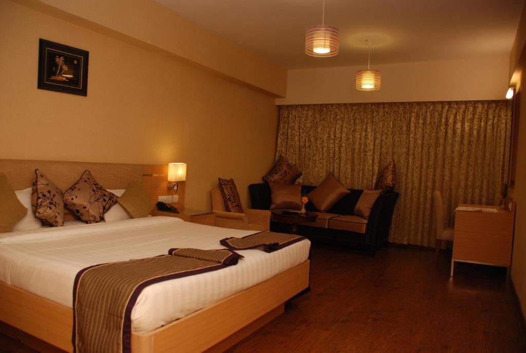 ein Hotelzimmer mit einem Bett und einem Sofa in der Unterkunft PLA Krishna Inn in Tiruchchirāppalli