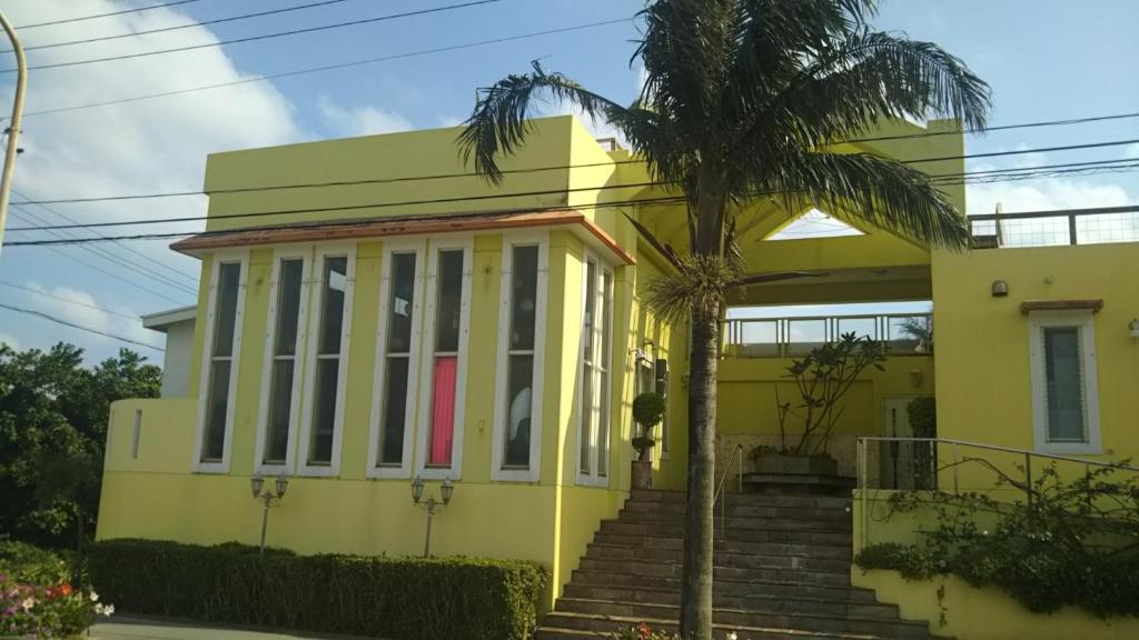 a yellow house with a palm tree in front of it at palmsﾌﾟﾗｲﾍﾞｰﾄプールから海と星空見える広々96平米 BBQ台 P5台分無料 wii WiFi in Ishigaki Island