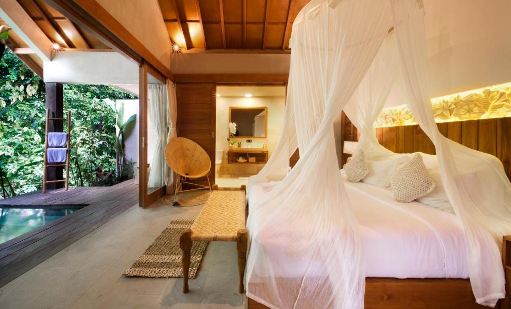 a bedroom with a bed with a mosquito net at Kalapa Boutique Resort & Yoga in Canggu