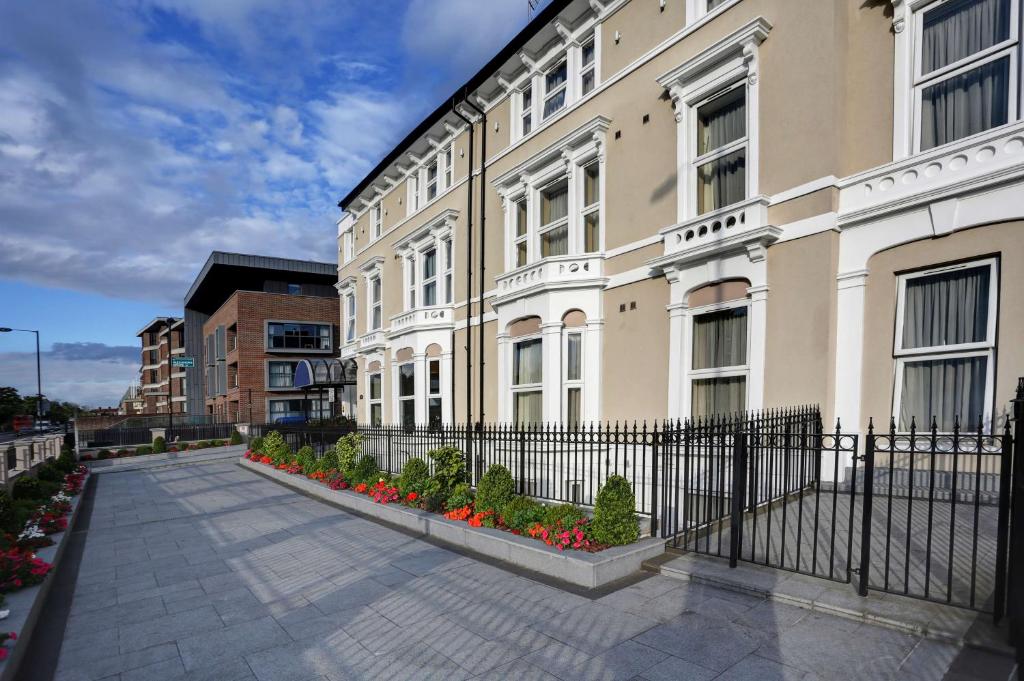 a building with a fence and flowers in front of it at Best Western London Highbury in London