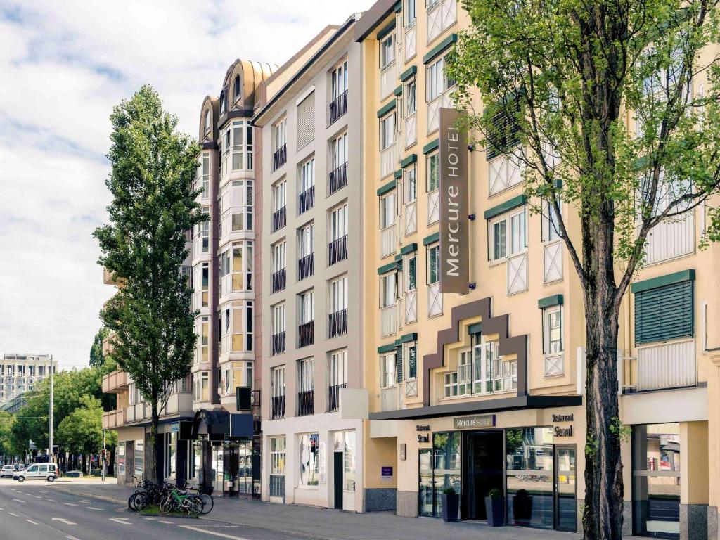 ein großes Gebäude an einer Stadtstraße mit Bäumen in der Unterkunft Mercure Hotel München-Schwabing in München