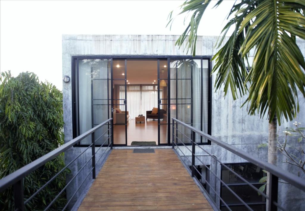 a wooden walkway leading to a house with glass doors at Baan Mali Apartment in Chiang Mai