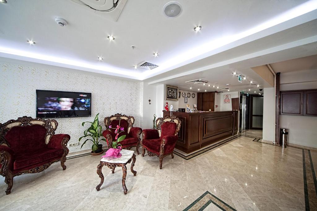 a living room with chairs and a tv on a wall at Istanbul Newcity Hotel in Istanbul
