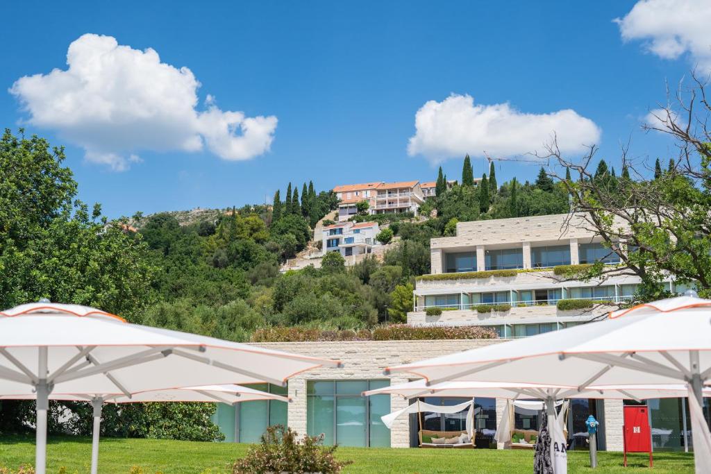 a resort with umbrellas in front of a building at Apartmani D & J in Orasac