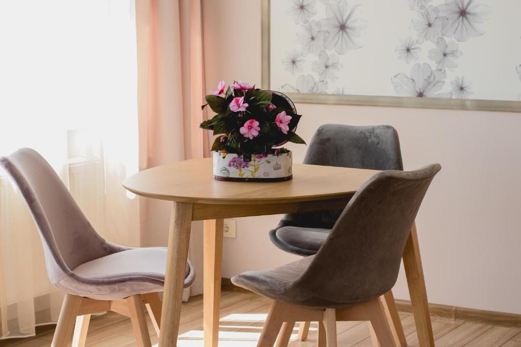 una mesa con dos sillas y un jarrón de flores. en Apartments in Joniškis, en Joniškis