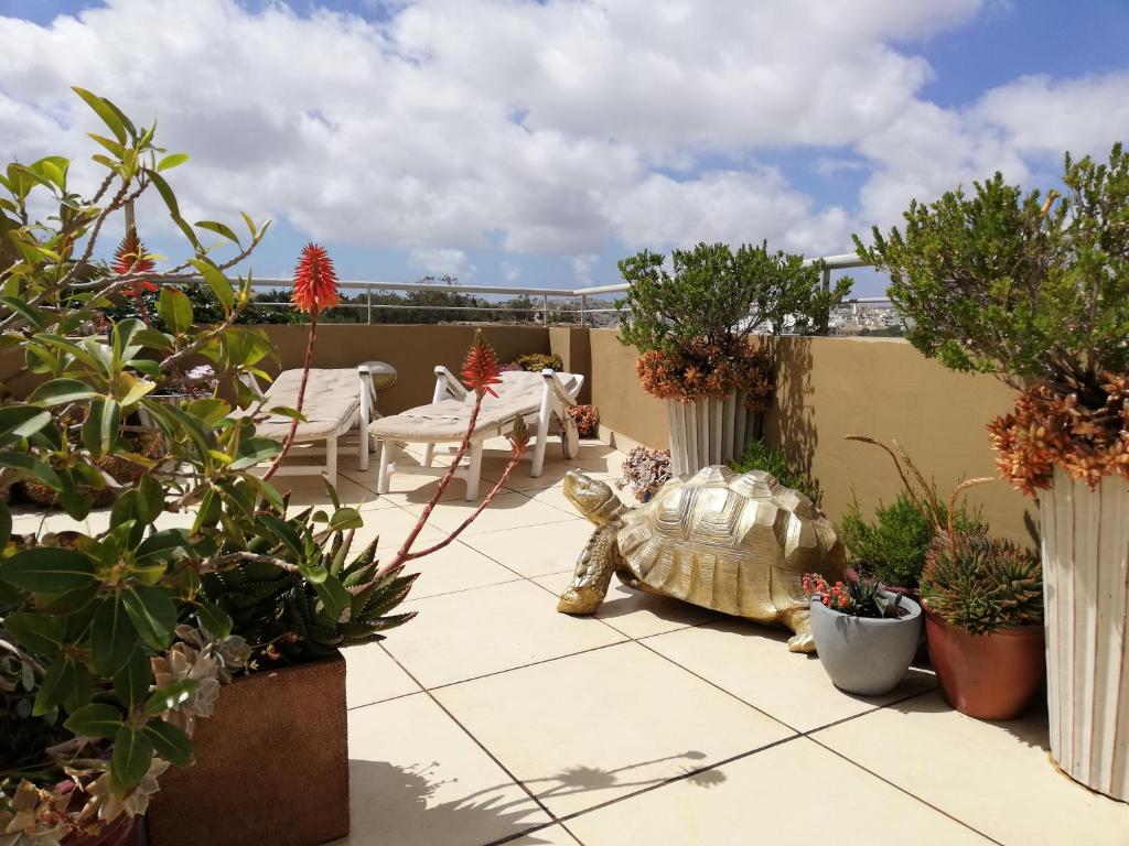 a turtle statue sitting on a patio with plants at Three Cities Apartments in Cospicua