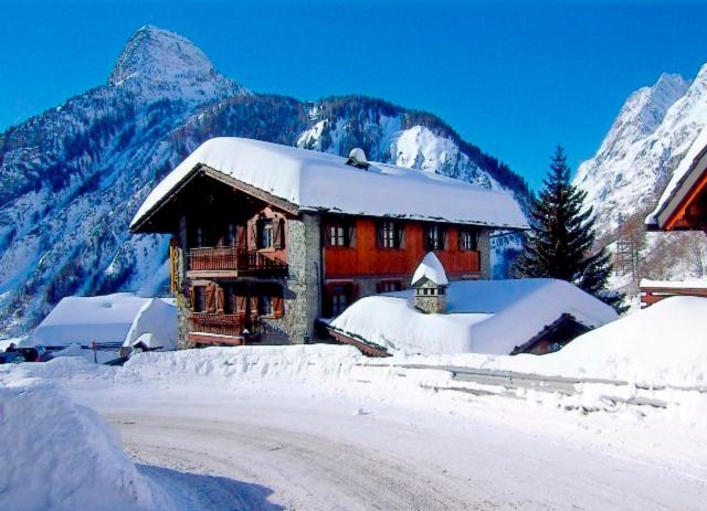 un edificio ricoperto di neve con montagne sullo sfondo di Hotel Dente Del Gigante a Courmayeur