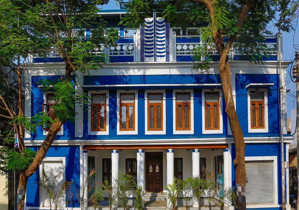 un edificio azul y blanco con árboles delante en Tanjore Hi Hotel, en Thanjāvūr