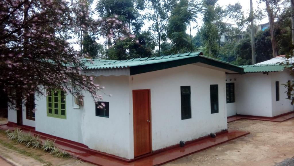a small white house with a green roof at Tree House Holiday Home in Bandarawela