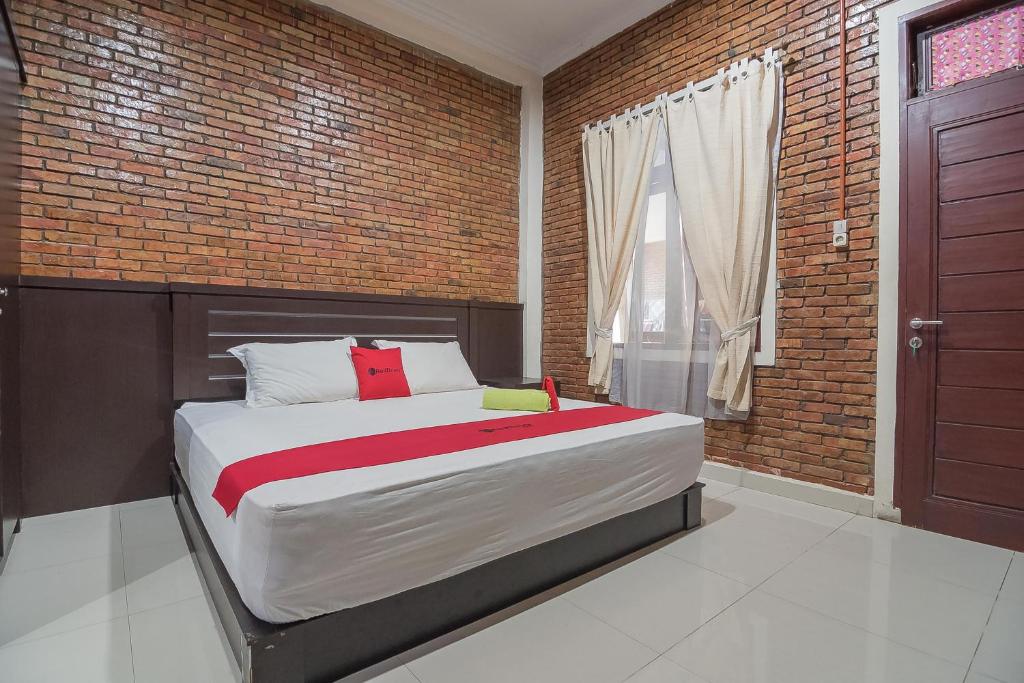 ein Schlafzimmer mit einem großen Bett mit Ziegelwand in der Unterkunft RedDoorz Plus near Cambridge City Square 2 Medan in Medan