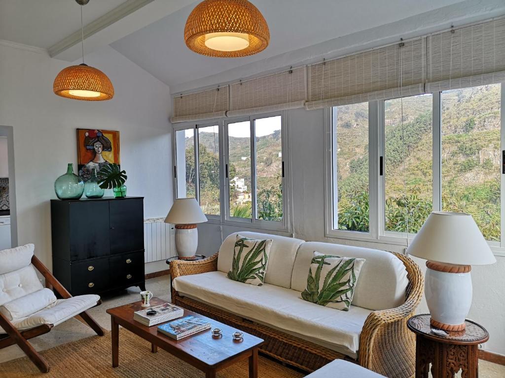 een woonkamer met een bank, stoelen en ramen bij Casa con Cuevita in Teror