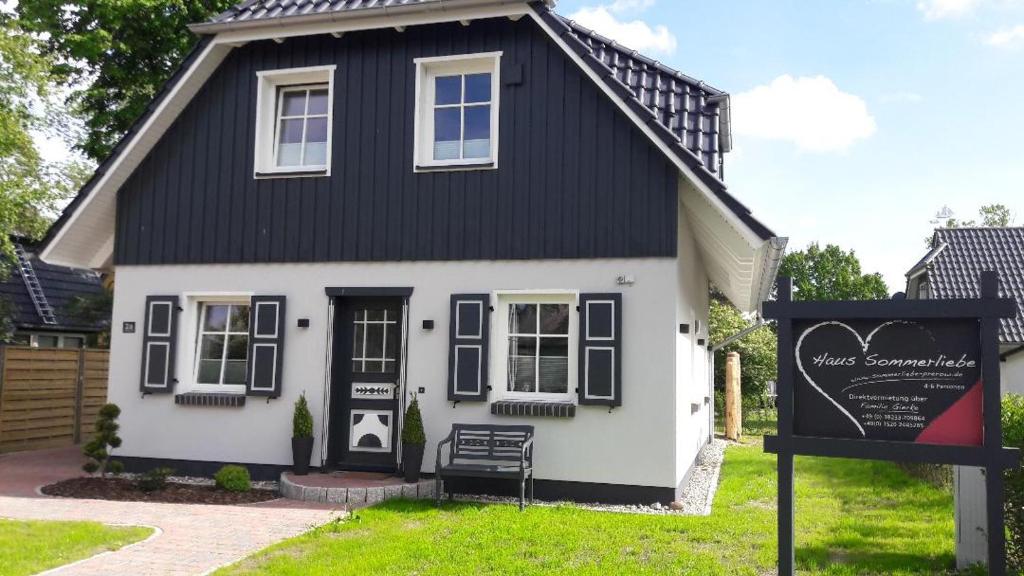 een zwart-wit huis met een bord ervoor bij Haus Sommerliebe in Prerow