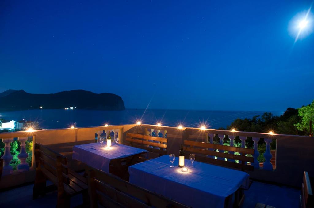 un restaurante con 2 mesas en un balcón por la noche en Castellamare Residence, en Petrovac na Moru