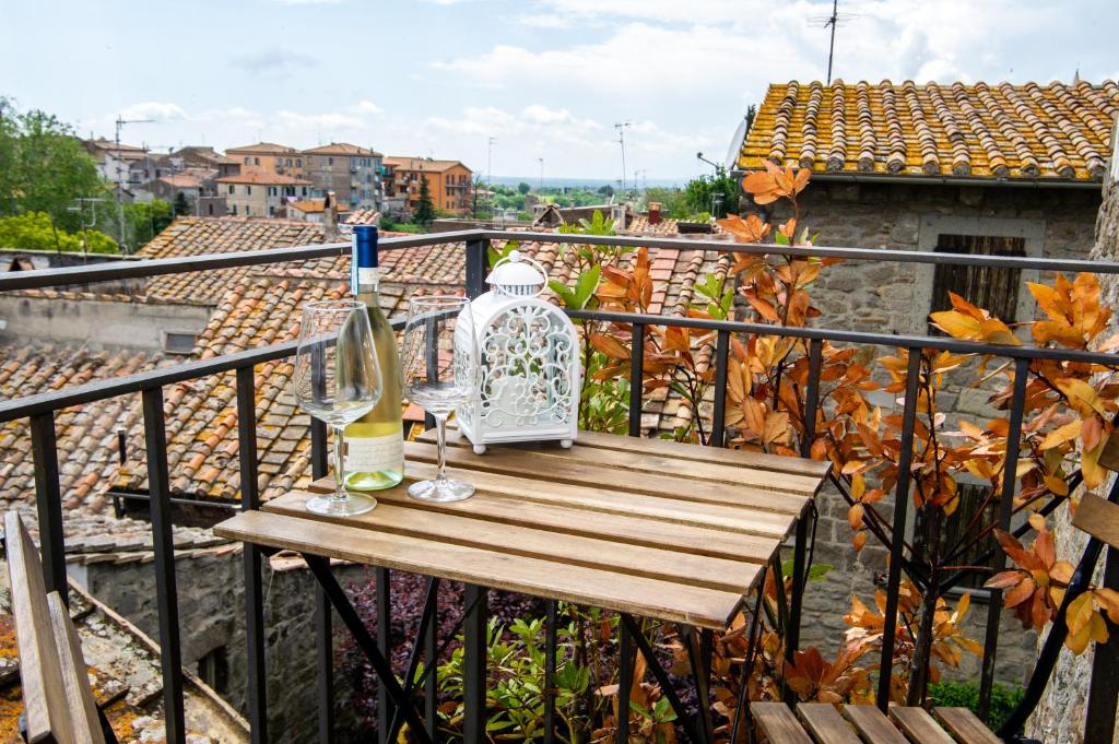 a wooden table with a vase and glasses on a balcony at La Suite del Borgo in Viterbo