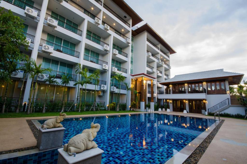 a hotel with a swimming pool in front of a building at Khammon Lanna Resort Chiang Mai in Chiang Mai