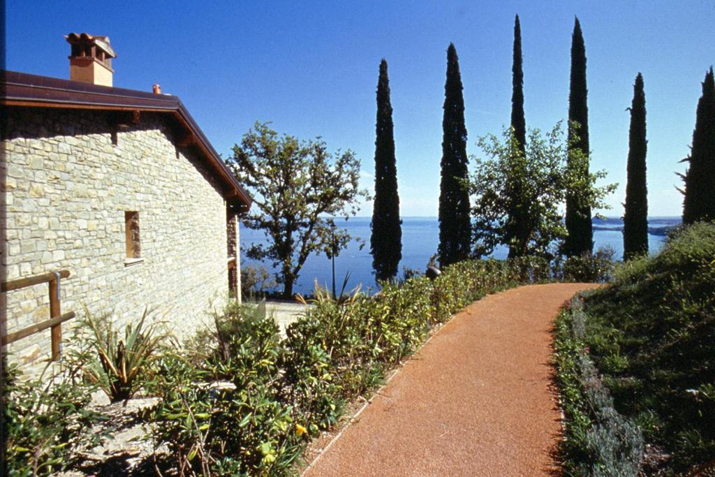 a path next to a building with a bunch of trees at Appartamenti Borgo in Gardone Riviera