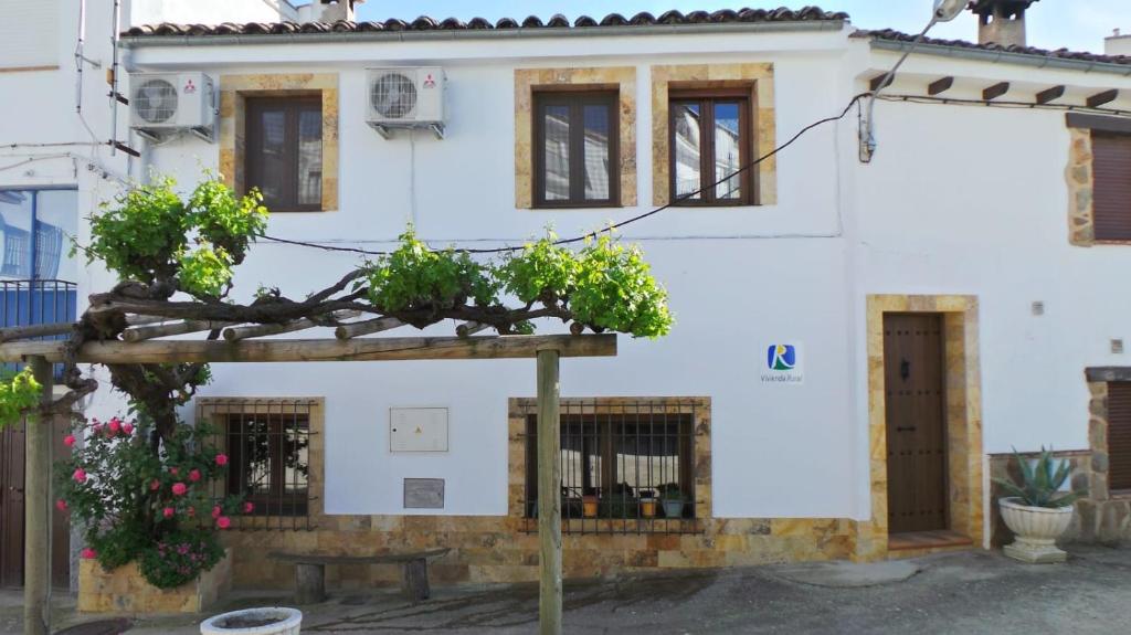 une maison blanche avec deux plantes en pot devant elle dans l'établissement Vivienda rural fuente de los gusarapos, à Burunchel