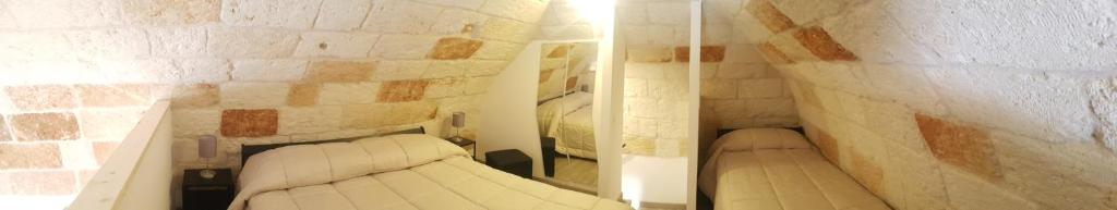 Cette chambre comprend 2 lits blancs dans un mur en briques. dans l'établissement Dimora Sasi Locazione Turistica, à Polignano a Mare