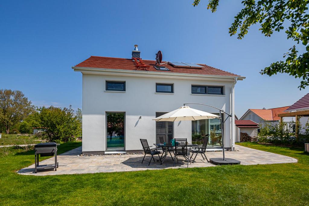 a white house with a table and chairs and an umbrella at Ferienhaus Rügen-Relax in Trent