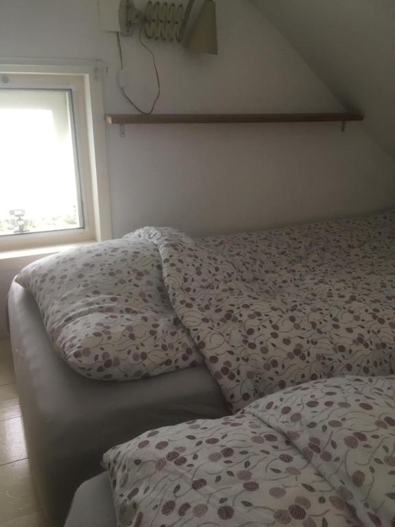 a bed with a blanket and a window in a room at Het Duinhuisje in Goedereede