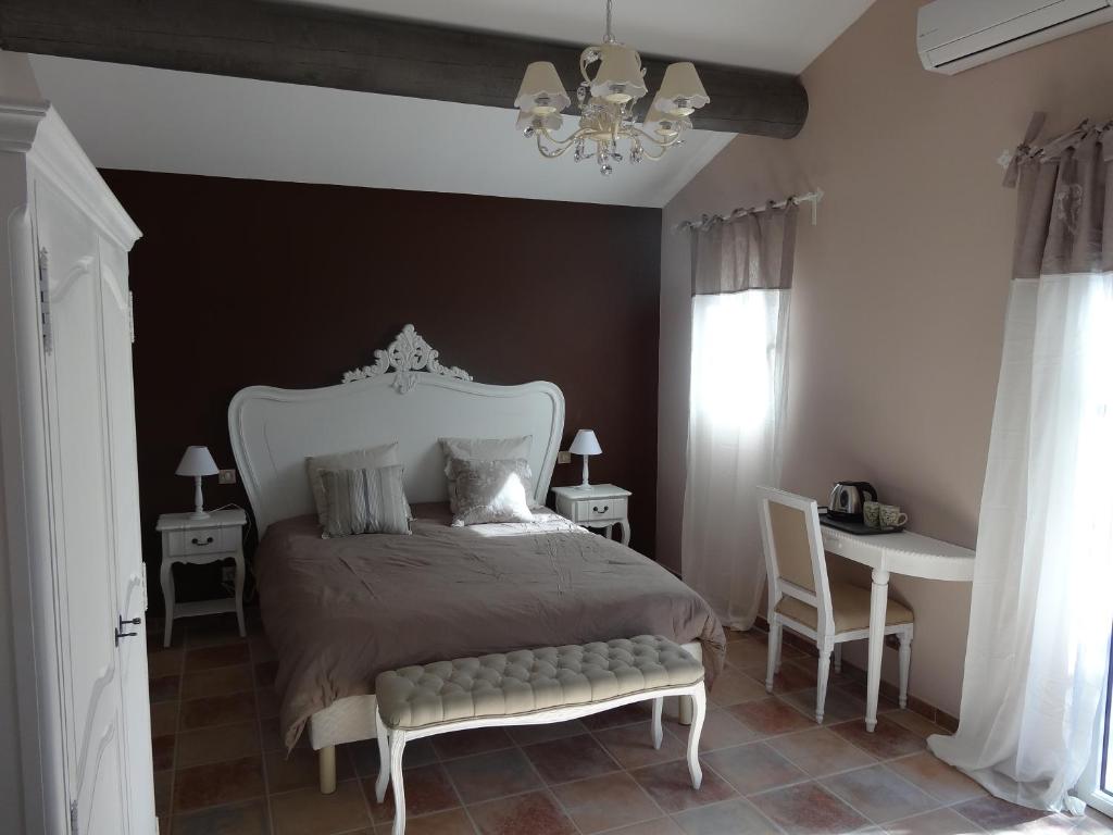 1 dormitorio con cama, mesa y lámpara de araña en Mas'Xime en Saint-Rémy-de-Provence