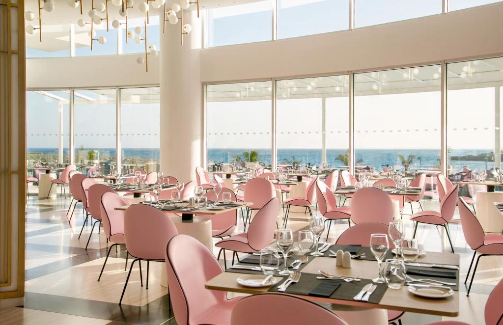 a dining room with pink chairs and tables at NissiBlu Beach Resort in Ayia Napa