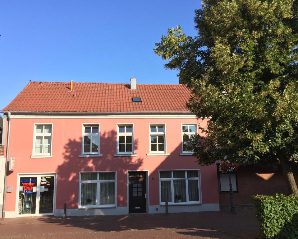 een oranje en roze huis met een boom bij Gästeapartment Kübel in Uedem