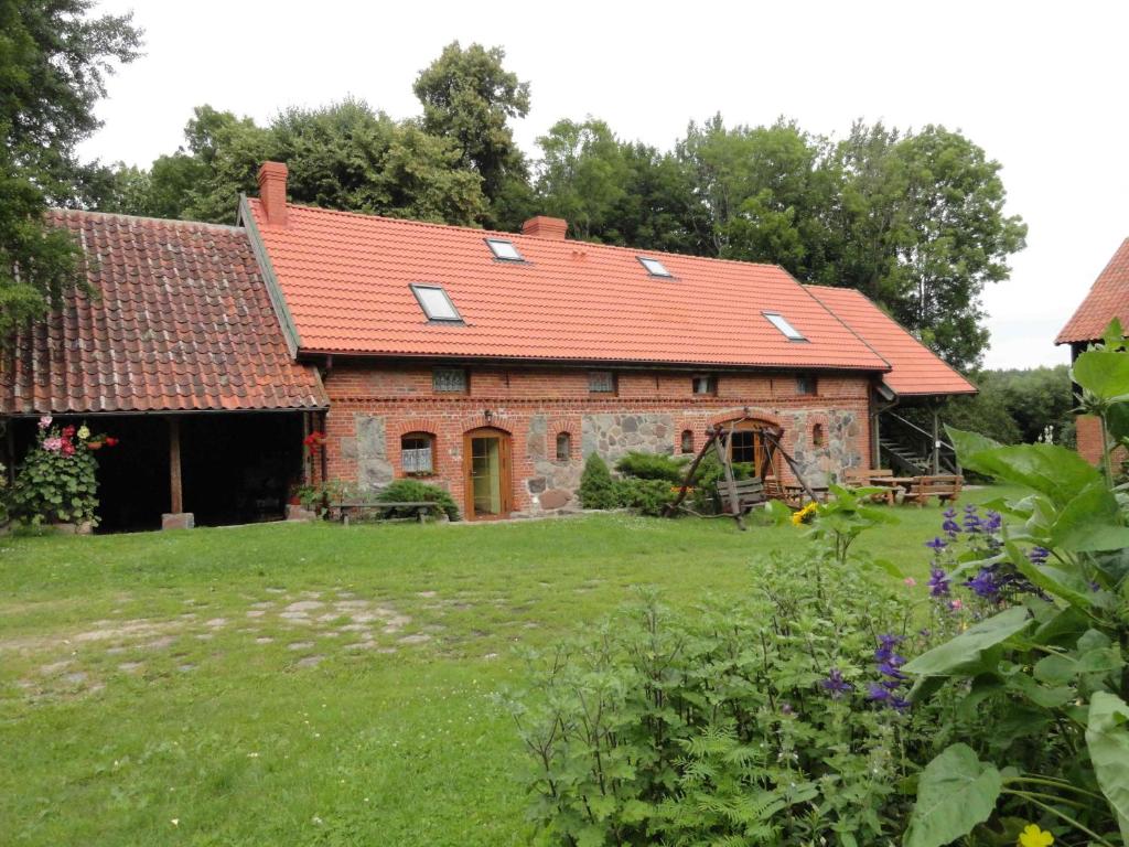 una antigua casa de ladrillo con techo rojo en Zagroda Cztery Wiatry, en Sądry