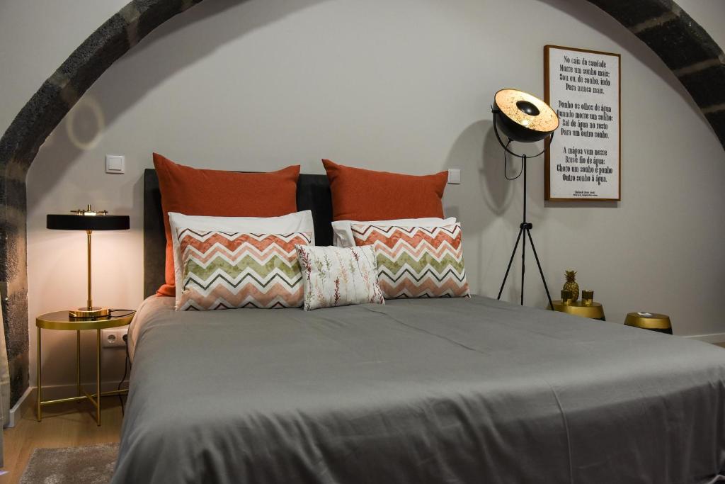 a bedroom with a large bed with orange pillows at Casa das Arcadas in Ponta Delgada