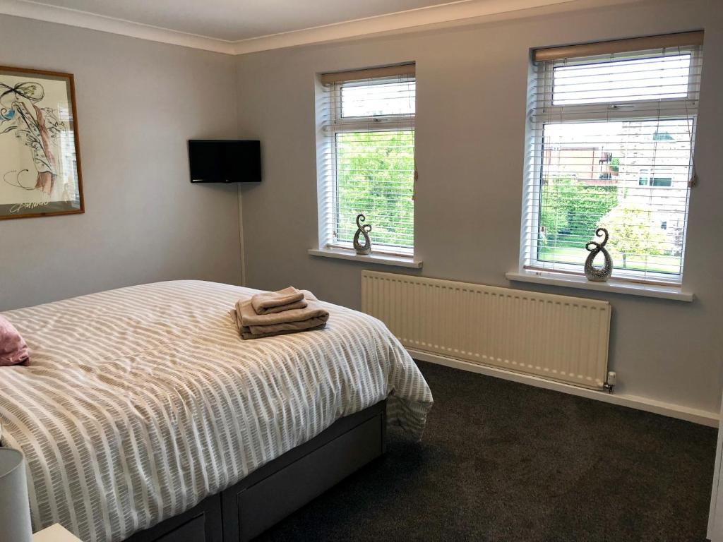 a bedroom with a bed and two windows at AB - Top floor 2 bed modern town centre apartment with parking for one vehicle in Stratford-upon-Avon