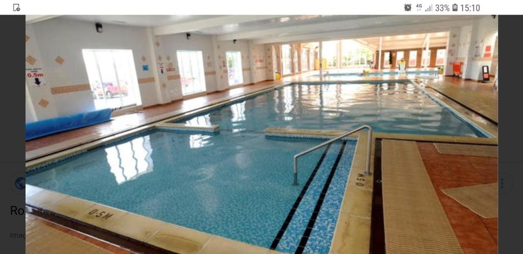 uma grande piscina interior com água azul em Holiday Home in Lyons Robin Hood Holiday Park em Meliden