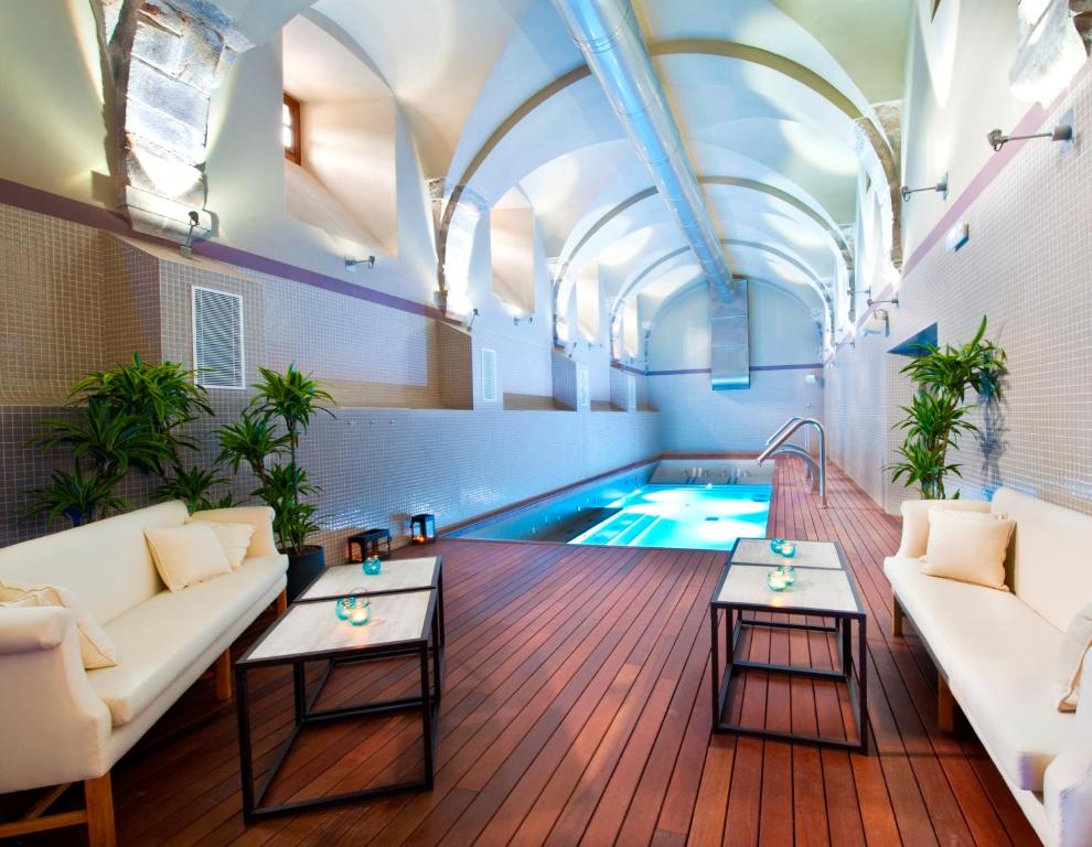sala de estar con piscina, sofá y mesas en Parador de Corias, en Cangas del Narcea