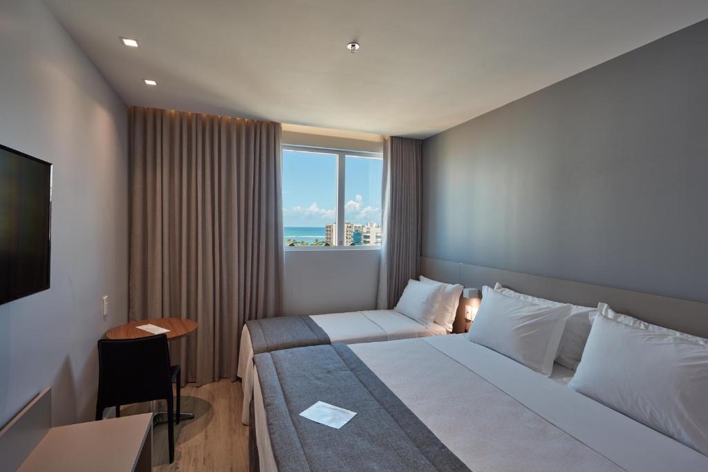 a hotel room with two beds and a window at Flix Hotel in Maceió