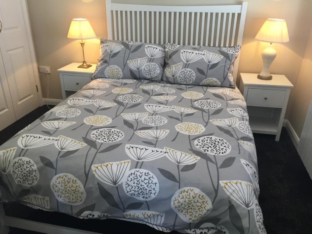 a bed with a gray and white comforter and pillows at Old Picture House in Seaton