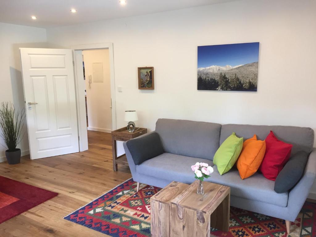 sala de estar con sofá gris y almohadas coloridas en Ferienwohnung Laurin en Garmisch-Partenkirchen