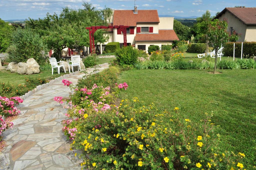 een tuin met stoelen en bloemen voor een huis bij Hôtel-Logis La Coraline in Gannat