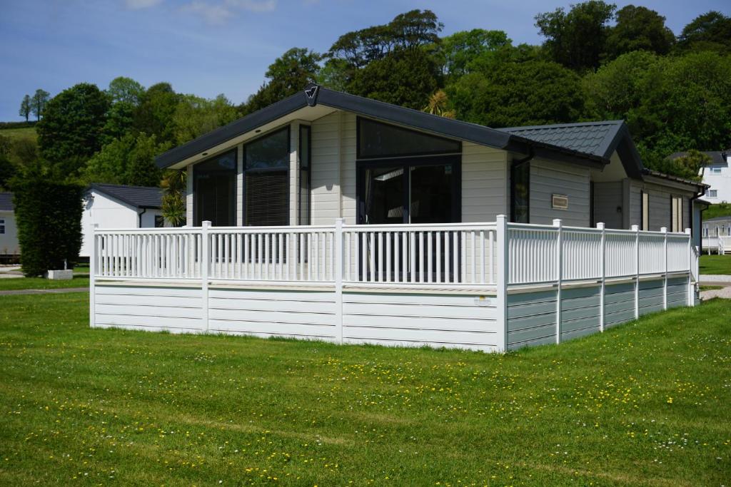 una casa con una valla blanca en un patio en Lodge 77 en St Austell