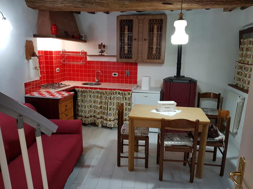 een keuken met een tafel en een keuken met rode tegels bij Luciano & Norma's House La Torre in Massa Marittima