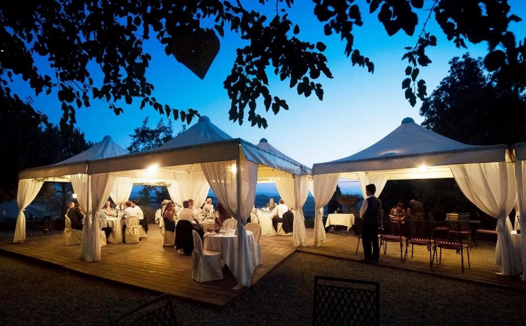 grupa ludzi siedzących pod namiotami na weselu w obiekcie Castello di Leonina Relais - Adults Only w Sienie