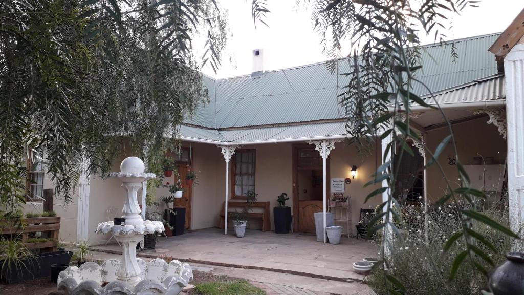 a house with a white fountain in the yard at Calvinia Guesthouse in Calvinia