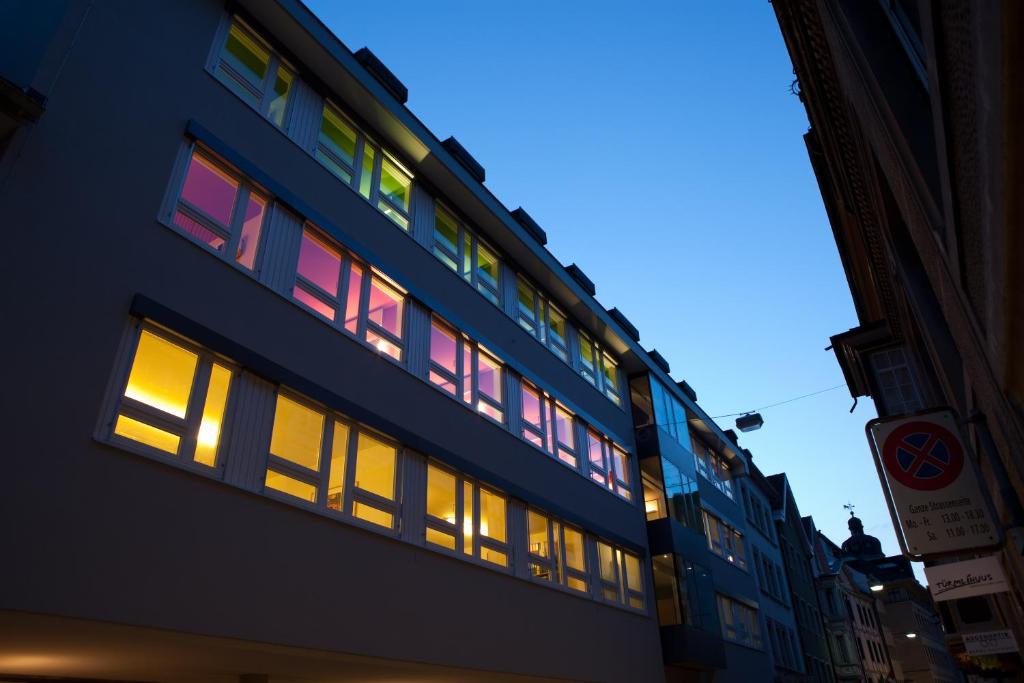 ein Gebäude mit beleuchteten Fenstern auf einer Straße in der Unterkunft Hotel Dom in St. Gallen