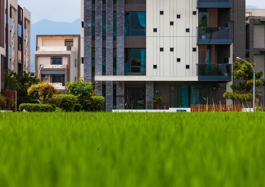 un edificio alto frente a un campo de hierba en Rambling Snail, en Luodong