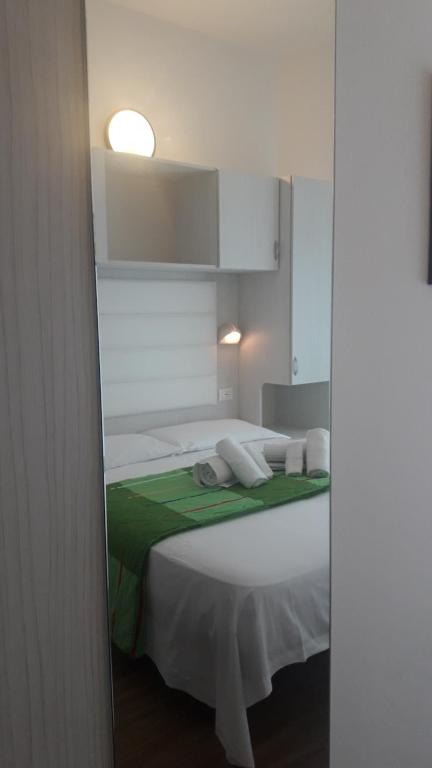 a bedroom with a white bed with a green blanket at Hotel Imperiale in Cesenatico