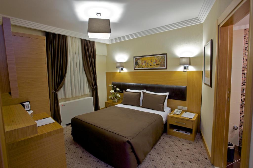 イスタンブールにあるMirilayon Hotel - Old Townのベッドとナイトスタンド付きのホテルルーム