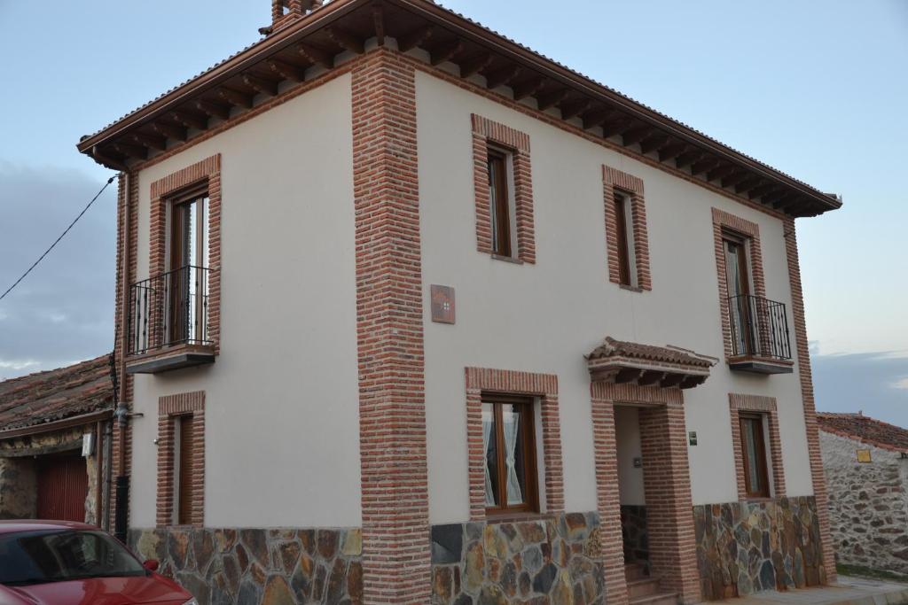 biały budynek z czerwonymi cegłami i oknami w obiekcie Casa Rural Casa Jacinta w mieście San Cristóbal de Segovia
