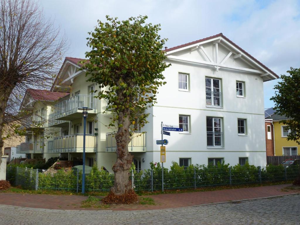 ein weißes Gebäude mit einem Baum davor in der Unterkunft Ferienwohnung am Rhododendronpark, 300 m zum Strand in Graal-Müritz