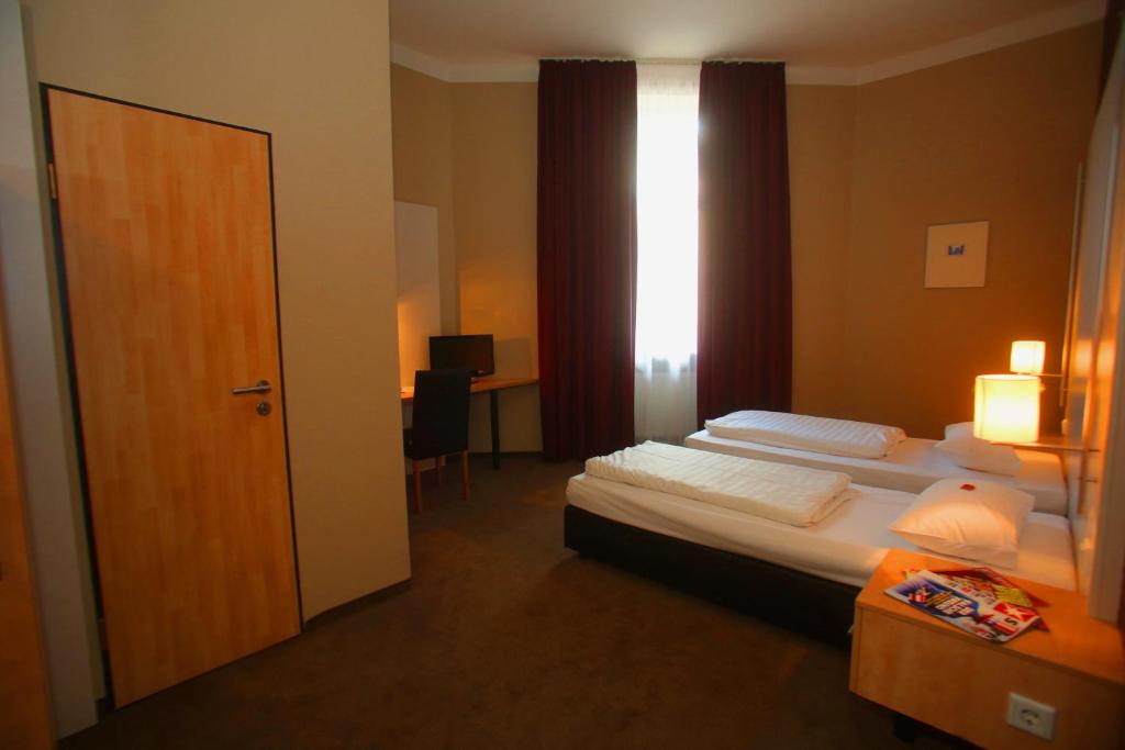 a hotel room with two beds and a window at Hotel Columbus in Frankfurt